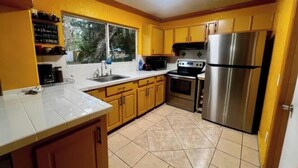 A kitchen with yellow cabinets, a stainless steel refrigerator, a microwave, and a stove. - A place to relax (LaBelle)