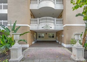 Ein Gebäudeeingang mit einem Doppelbalkon, einem Schild mit der Aufschrift '7658 WHISPER WAY' und zwei großen Pflanzkästen.