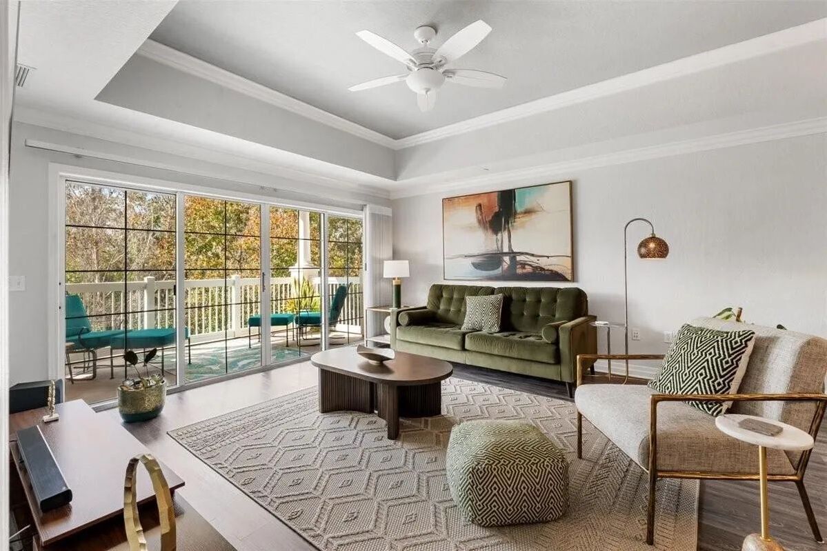 Living room with an olive green sofa and sliding glass doors opening to a deck.