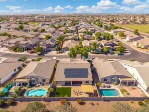 A residential area with houses, a swimming pool, and a clear sky. - Spacious 4-Bedroom Home ~ Backyard BBQ Oasis (Phoenix)