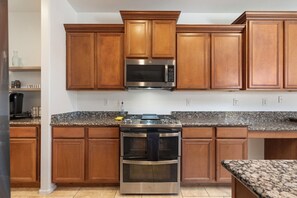 Eine Küche mit Holzausstattung, einer Edelstahl-Mikrowelle und einem eingebauten Backofen.