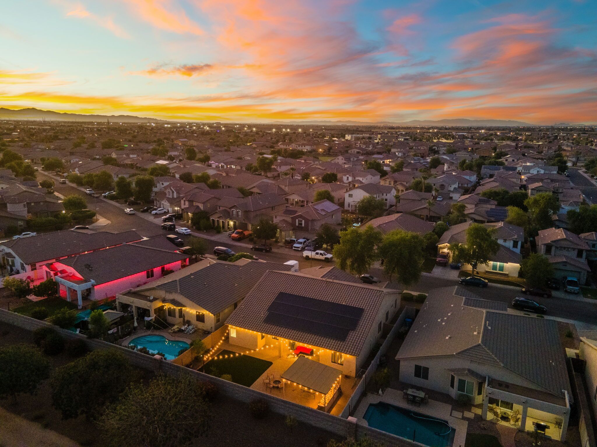 Vista aérea de una zona residencial con casas, una piscina y un edificio grande con techo rojo.