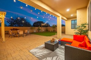 Une terrasse extérieure avec un espace salon, une petite table et des guirlandes lumineuses.