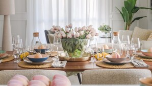 Et spisebord dækket med vinglas, tallerkener og en vase med blomster.