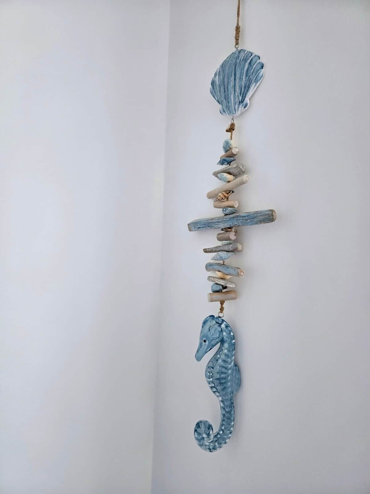 A vertical arrangement of decorative elements including a seashell, wooden slats, and a seahorse.