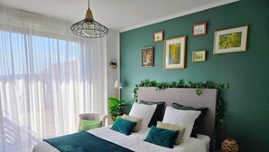 A bedroom with a bed, a bedside table, a lamp, and framed pictures on the wall.