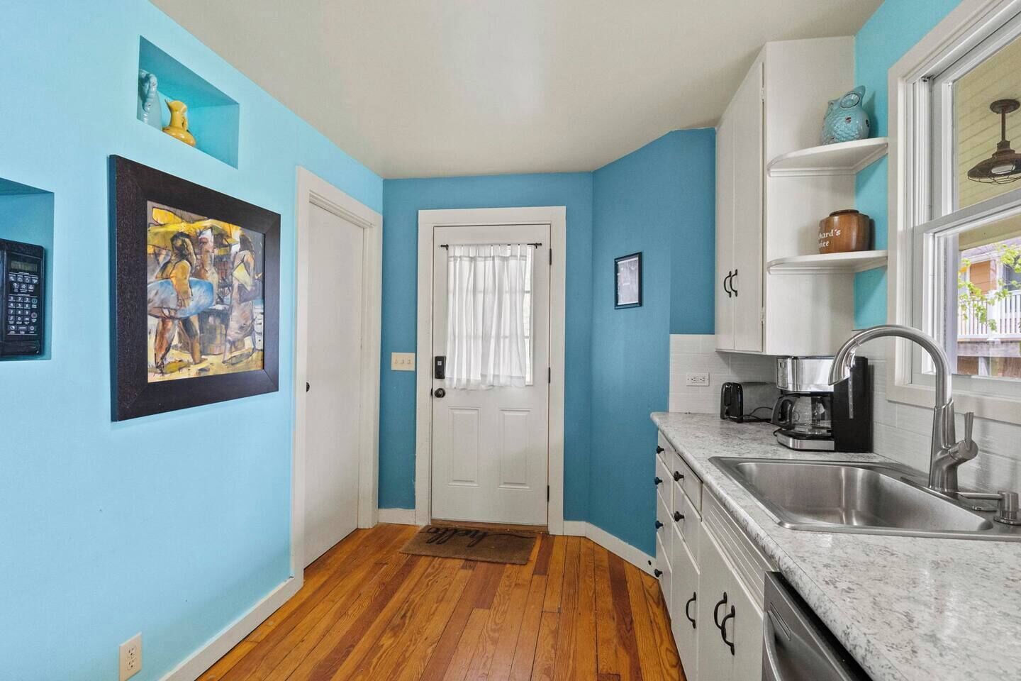 Una cocina con un lavamanos, armarios y una puerta con ventanal.