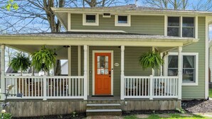 A two-story house with a porch, a front door, and a mailbox.