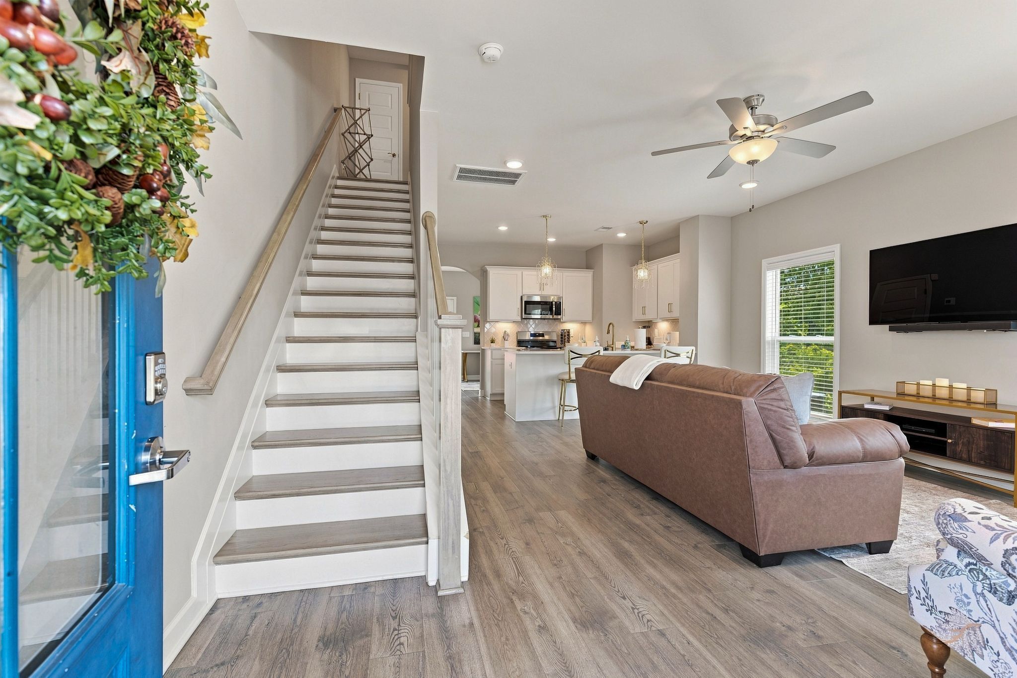 Ein modernes Interieur mit Treppe, Wohnbereich mit Sofa, Küche und Fernseher.