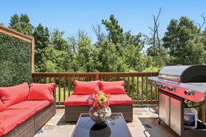Eine Terrasss mit Korbmöbeln, einem Grill und einem Gasbehälter.
