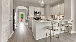 A modern kitchen with white cabinetry, a central island with bar stools, and pendant lighting. - Stylish Antioch Stay Minutes to Downtown Nashville (Nashville)