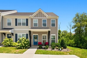 A two-story residential building with a front porch, a blue door, and a small garden with shrubs and a pathway leading to the entrance. - Stylish Antioch Stay Minutes to Downtown Nashville (Nashville)