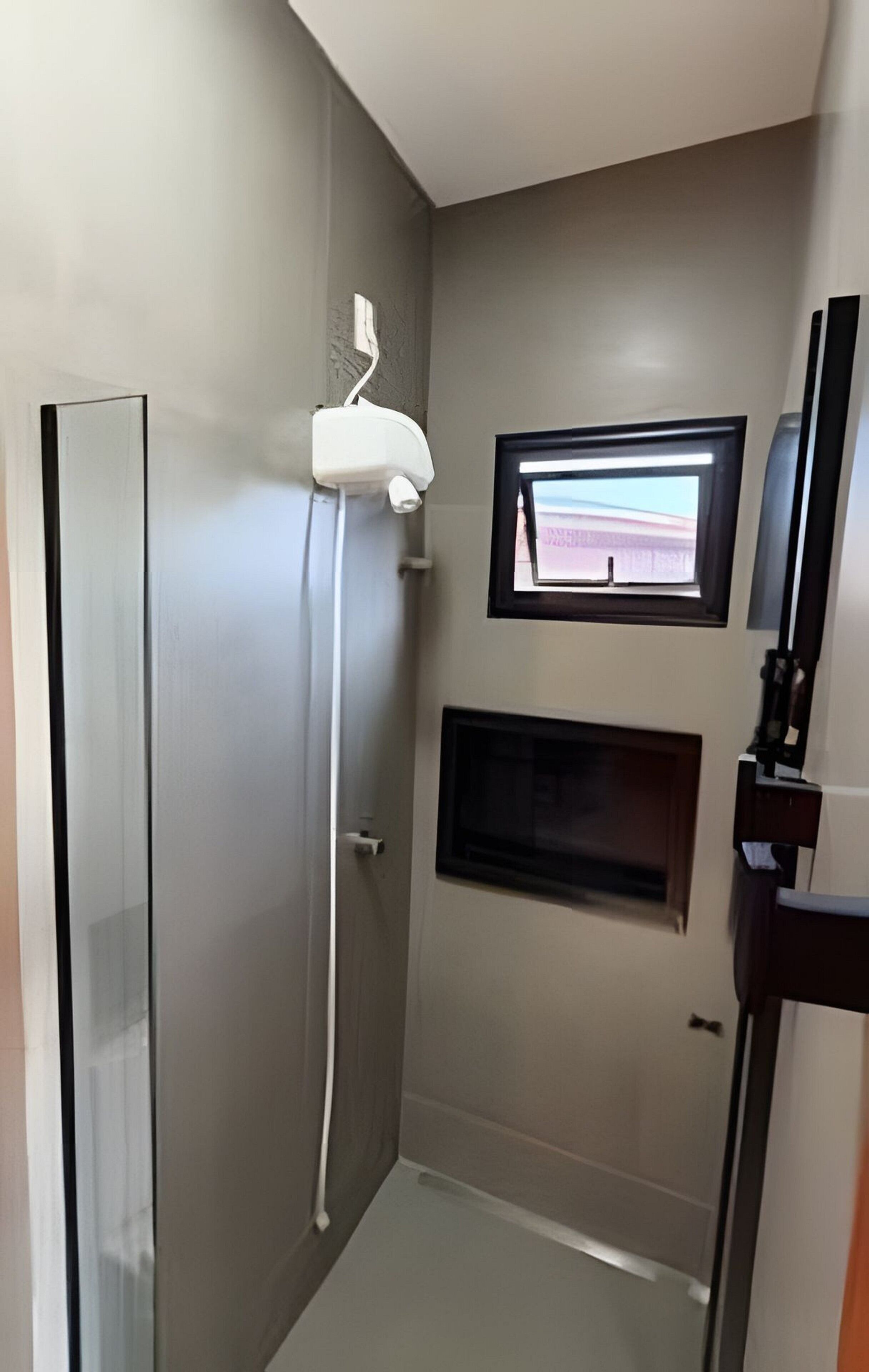 Une salle de bain avec une douche, un miroir et une fenêtre.
