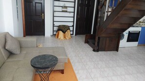 A living room with a sofa, a round table, a staircase, and a washing machine.