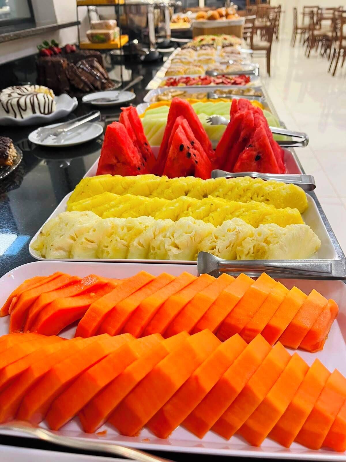 Een buffet met diverse soorten eten, waaronder watermeloen, ananas en mango.