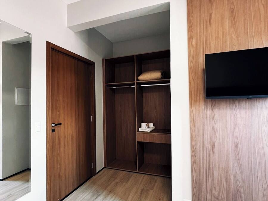 Una habitación con un armario de madera, un televisor de pantalla plana en la pared y un suelo de madera claro.
