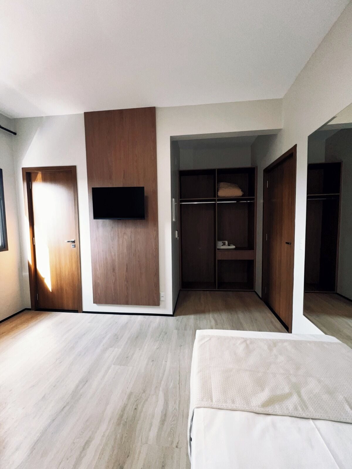A bedroom with a bed, a wardrobe, a television, and a closet.