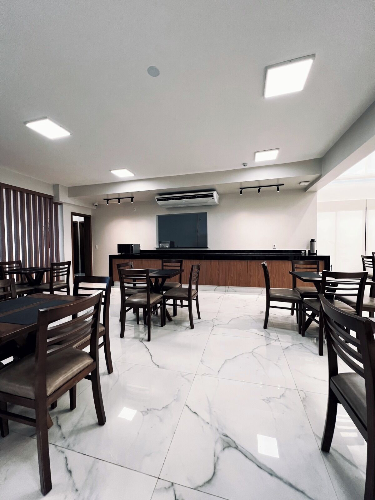 Un salón de conferencias con piso de mármol, mesas y sillas de madera.