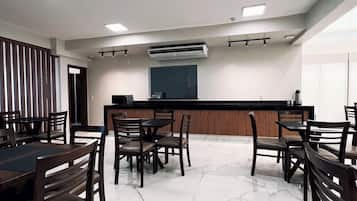 Un salón de conferencias con piso de mármol, mesas y sillas de madera.