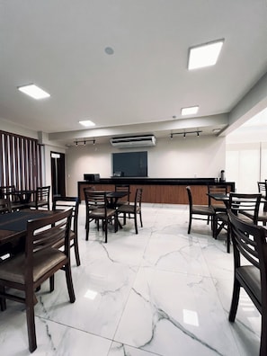 A conference room with a marble floor, wooden tables, and chairs.