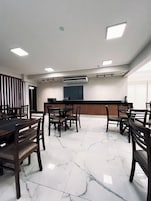 Uma sala de conferências com piso de mármore, mesas e cadeiras de madeira.