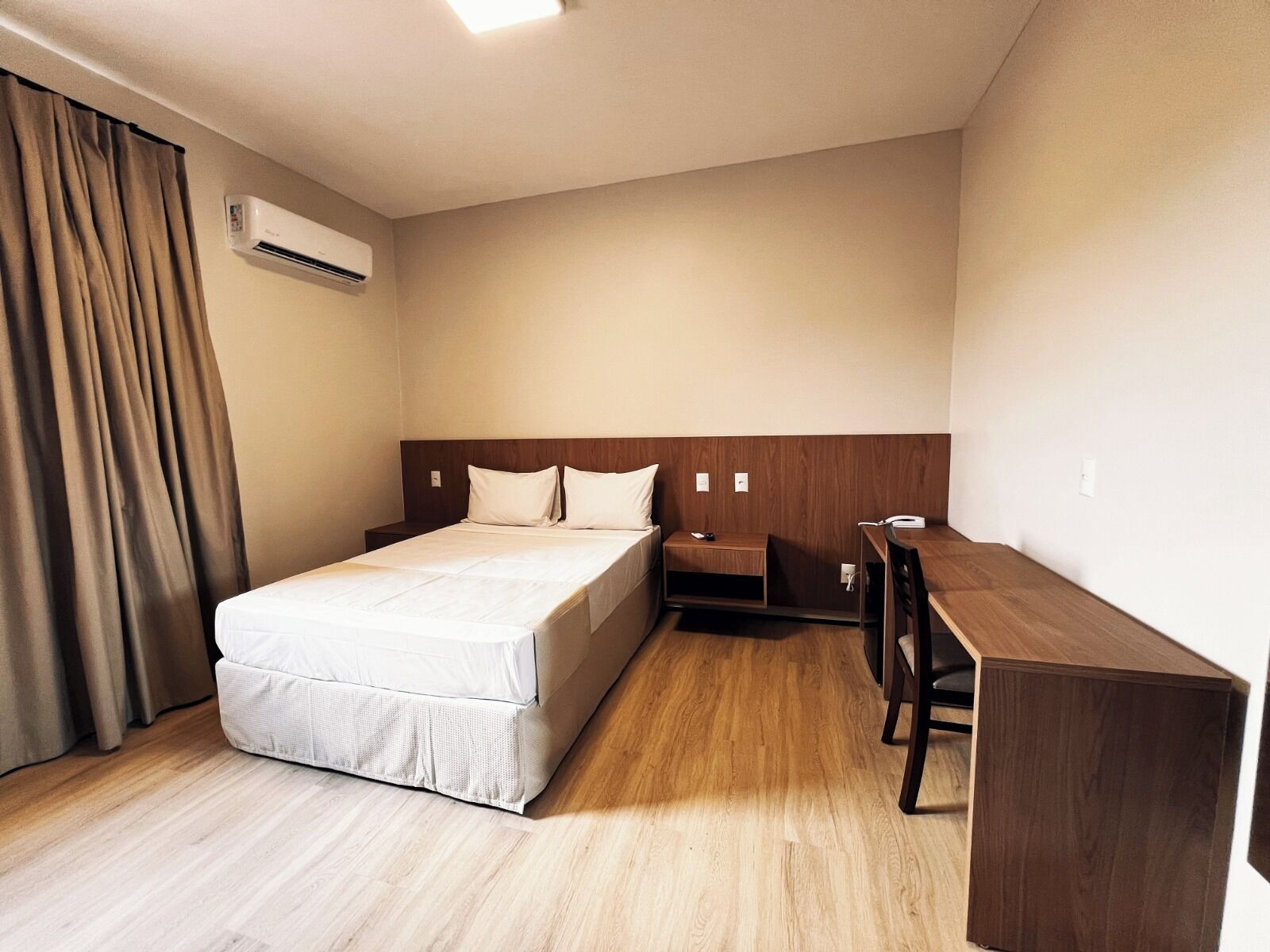 Una habitación de hotel con cama, escritorio y aire acondicionado.