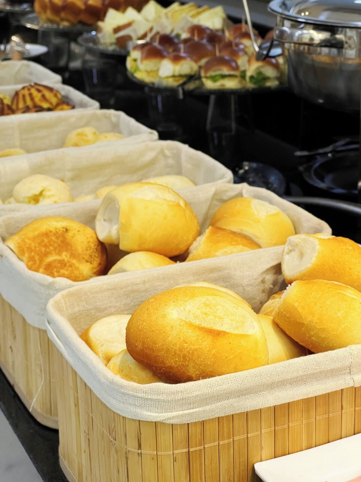 A buffet with various food items, including bread rolls and sandwiches.