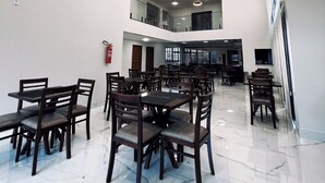 A spacious dining area with multiple tables and chairs, a fire extinguisher on the wall, and a modern ceiling design with recessed lighting. - Rota Hotéis Rio Verde (Rio Verde)