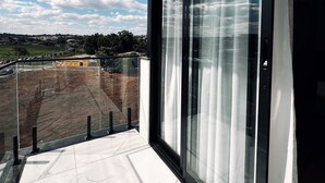A balcony with a glass door and a view of a construction site. - Rota Hotéis Rio Verde (Rio Verde)