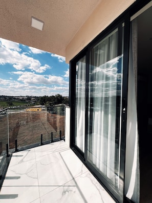 A balcony with a glass door and a view of a construction site.