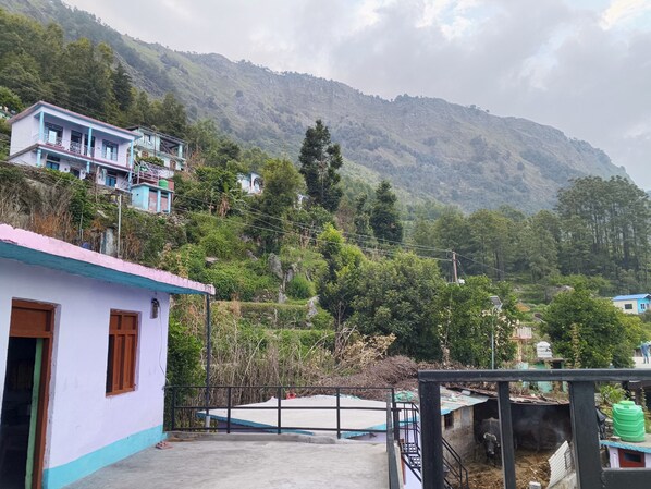 A rural setting with a small building, a fenced area, and a mountainous backdrop.
