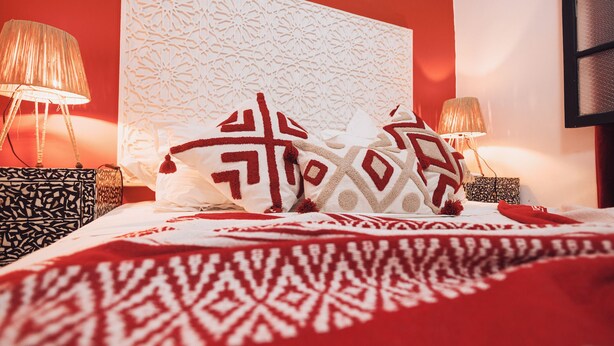 Un letto con biancheria a motivi decorativi, una parete decorata e due abat-jour.