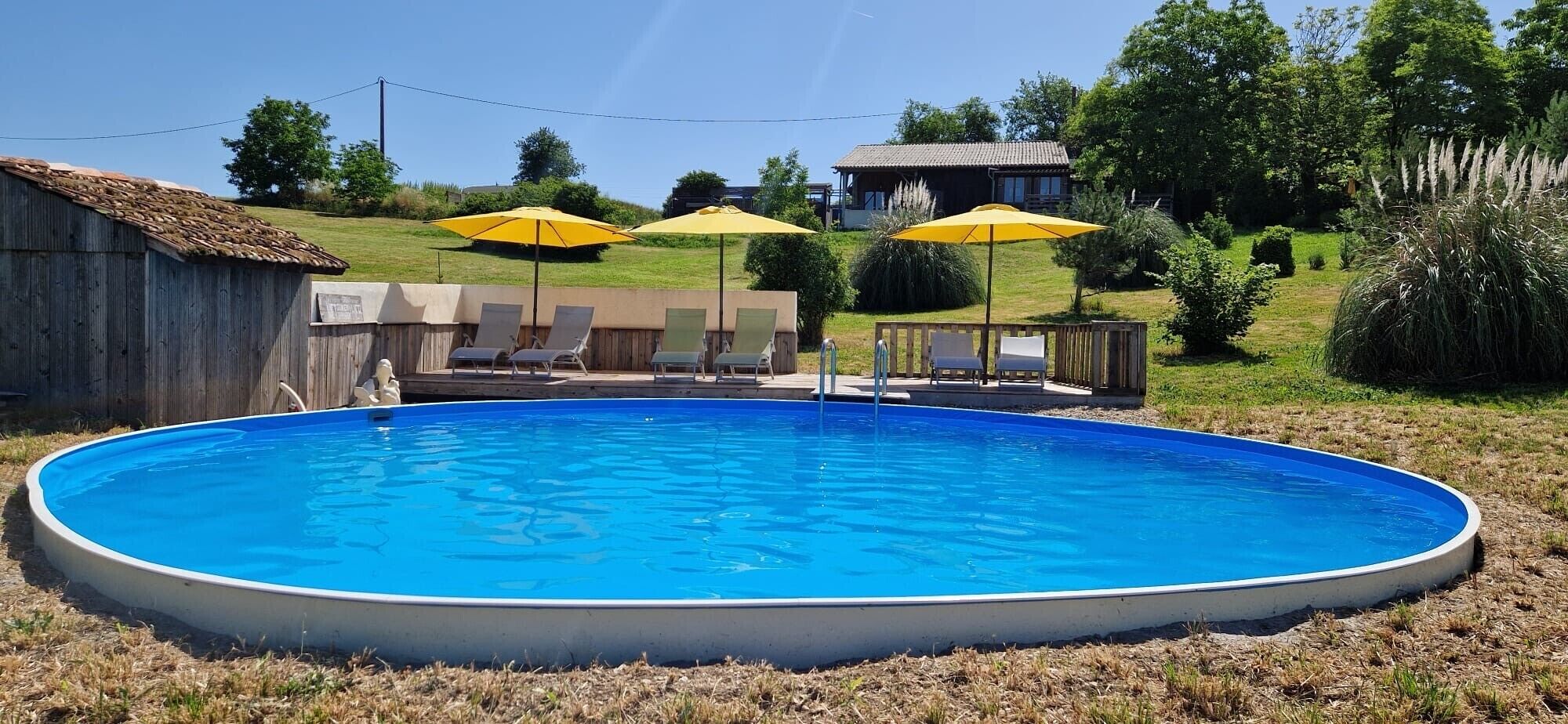 An above-ground swimming pool with lounge chairs and umbrellas.