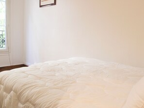 Une pièce avec un lit, une fenêtre et une porte.
