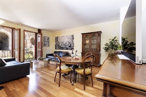 A dining area with a wooden table, chairs, a sofa, and a cabinet. - Exclusive Verona Apartment - Arena Views, 3 Bedrooms, Wi-fi (Verona)