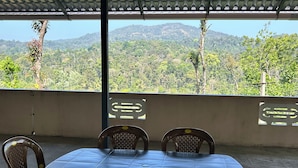 Un área de comedor al aire libre con una mesa y sillas, con vista a un paisaje montañoso.