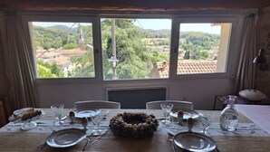 A dining table set for six with a view of a rural landscape through large windows.