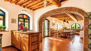 A spacious kitchen with a wooden island, a dining area with a brick archway, and a view of the outdoors. - La Casina: Detached villa with swimming pool, hot tub, and panoramic view. (Riparbella)