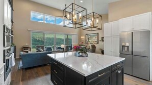 Una cocina moderna con una isla grande, electrodomésticos integrados y un comedor con vistas.