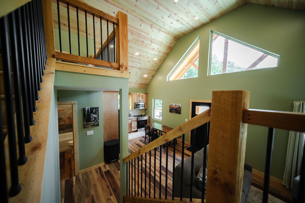 A multi-level interior with a wooden staircase, a kitchen area, and a dining space.