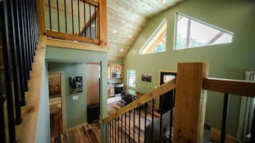 A multi-level interior with a wooden staircase, a kitchen area, and a dining space.