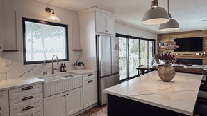Een moderne keuken met witte kasten, een groot eiland en een houten vloer.