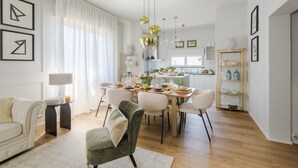 Ein moderner Essbereich mit einem für vier Personen gedeckten Tisch, umgeben von Stühlen, und eine Küche im Hintergrund.
