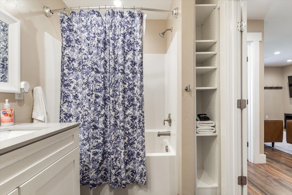 A bathroom with a shower curtain, a bathtub, a toilet, and a sink.