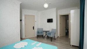A room with a bed, two chairs, a small table, a TV, and a door leading to another room. - Toma Palace (Khelvachauri)