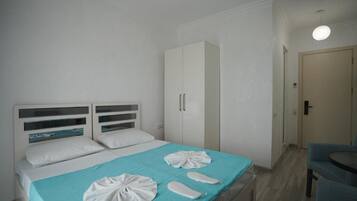 A hotel room with a bed, a wardrobe, a desk, and a chair.