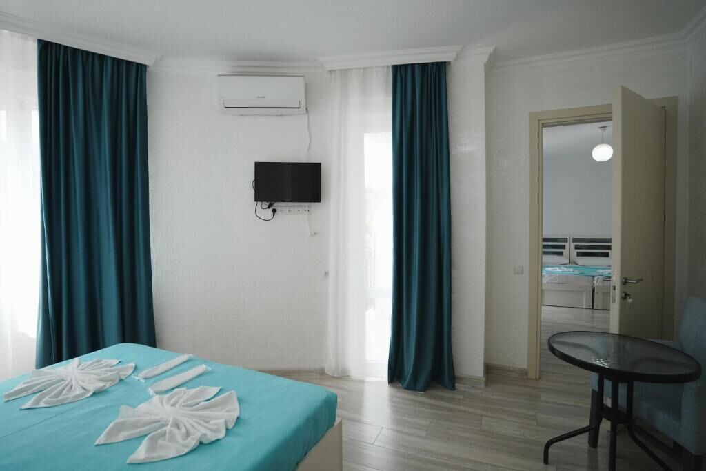 Habitación de hotel con cama, televisor, mesa y vistas al exterior.