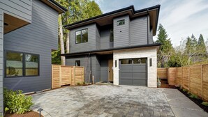A modern two-story house with a garage, a paved driveway, and wooden fences. - Bright + Modern DADU near Downtown Kirkland - Garage/EV +Private yard (Kirkland)