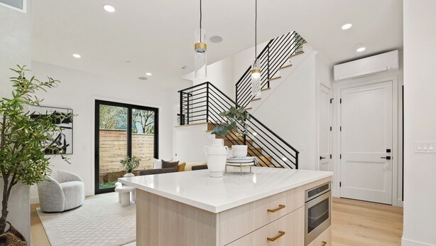 A modern kitchen with a central island, a staircase with black railings, and a large window. - Bright + Modern DADU near Downtown Kirkland - Garage/EV +Private yard (Kirkland)