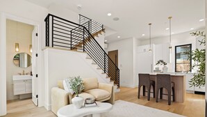 A modern living room with a staircase, a sofa, a coffee table, and a kitchen area. - Bright + Modern DADU near Downtown Kirkland - Garage/EV +Private yard (Kirkland)